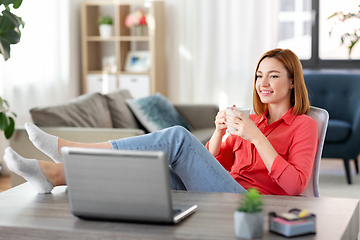 Image showing woman with laptop drinking coffee at home office