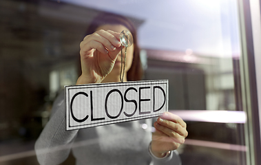 Image showing woman hanging banner with closed word on door