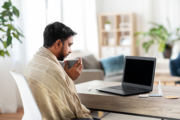 Image showing sick young man in blanket drinking hot tea at home