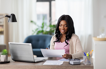 Image showing happy woman with laptop and papers at home office