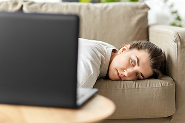 Image showing bored woman with laptop lying on sofa at home