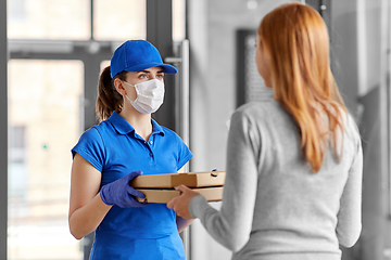 Image showing delivery girl in mask giving pizza boxes to woman