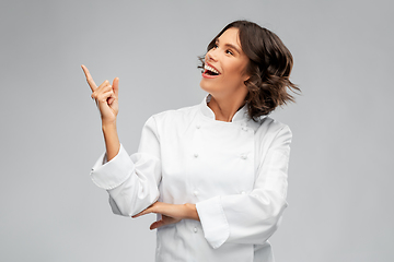 Image showing smiling female chef in toque pointing finger up