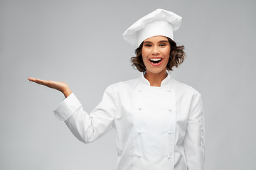 Image showing smiling female chef holding something on hand