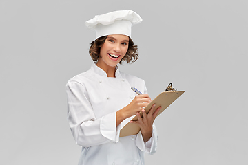 Image showing smiling female chef in toque with clipboard