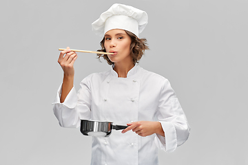 Image showing female chef with saucepan tasting food