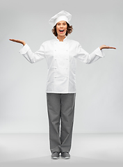 Image showing smiling female chef holding something on hand