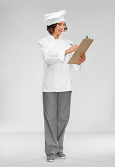 Image showing smiling female chef in toque with clipboard