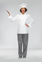 Image showing smiling female chef holding something on hand