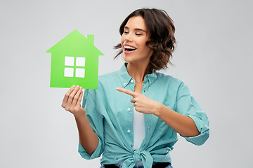 Image showing smiling young woman showing green house