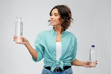 Image showing smiling young woman comparing bottles of water