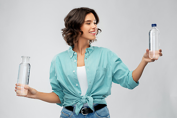 Image showing smiling young woman comparing bottles of water