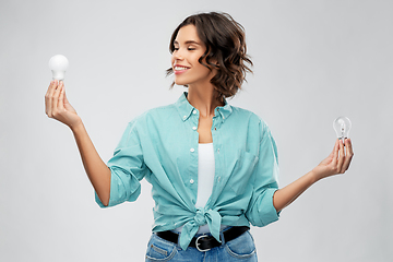 Image showing smiling woman comparing different light bulbs