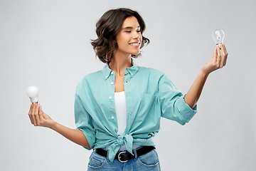 Image showing smiling woman comparing different light bulbs