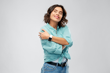 Image showing smiling woman with smart watch hugging herself