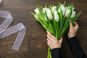 Image showing Florist at work: woman making fashion modern bouquet of different flowers on wooden background