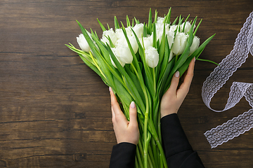 Image showing Florist at work: woman making fashion modern bouquet of different flowers on wooden background