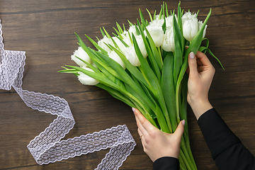 Image showing Florist at work: woman making fashion modern bouquet of different flowers on wooden background