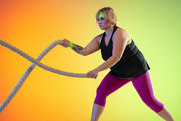 Image showing Young caucasian plus size female model\'s training on gradient orange background