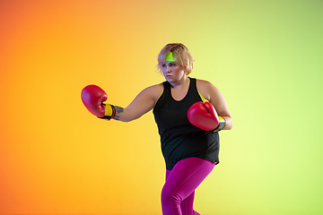 Image showing Young caucasian plus size female model\'s training on gradient orange background