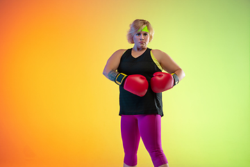 Image showing Young caucasian plus size female model\'s training on gradient orange background