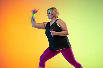 Image showing Young caucasian plus size female model\'s training on gradient orange background