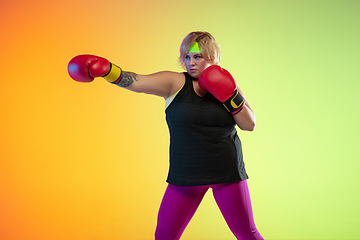 Image showing Young caucasian plus size female model\'s training on gradient orange background