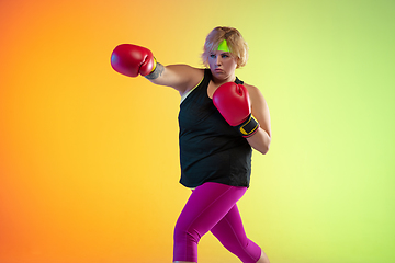 Image showing Young caucasian plus size female model\'s training on gradient orange background