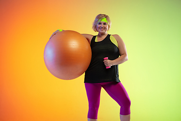 Image showing Young caucasian plus size female model\'s training on gradient orange background