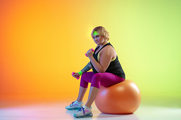 Image showing Young caucasian plus size female model\'s training on gradient orange background