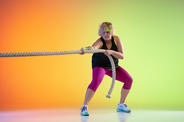 Image showing Young caucasian plus size female model\'s training on gradient orange background