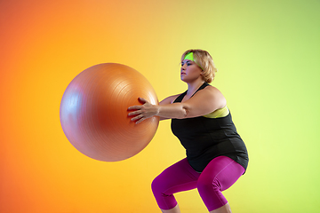 Image showing Young caucasian plus size female model\'s training on gradient orange background