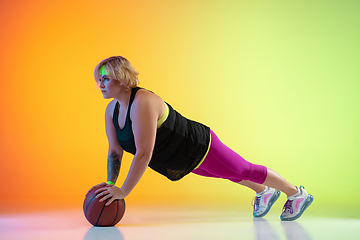 Image showing Young caucasian plus size female model\'s training on gradient orange background