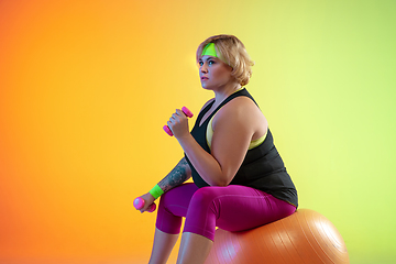 Image showing Young caucasian plus size female model\'s training on gradient orange background