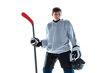 Image showing Young male hockey player with the stick on ice court and white background