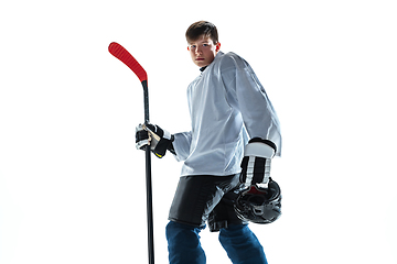 Image showing Young male hockey player with the stick on ice court and white background