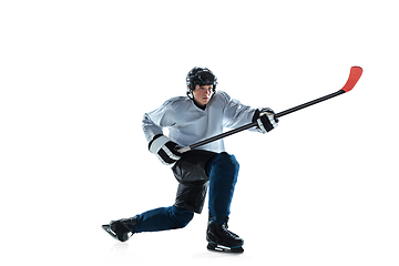 Image showing Young male hockey player with the stick on ice court and white background