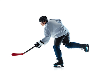 Image showing Young male hockey player with the stick on ice court and white background