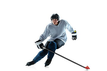 Image showing Young male hockey player with the stick on ice court and white background