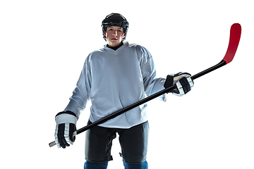 Image showing Young male hockey player with the stick on ice court and white background