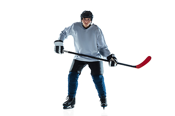 Image showing Young male hockey player with the stick on ice court and white background