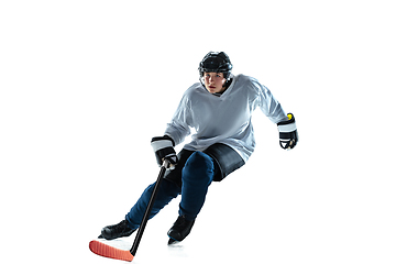 Image showing Young male hockey player with the stick on ice court and white background