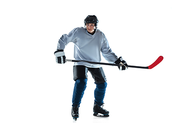 Image showing Young male hockey player with the stick on ice court and white background