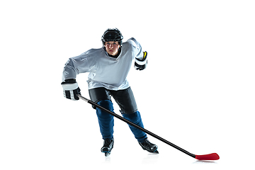 Image showing Young male hockey player with the stick on ice court and white background