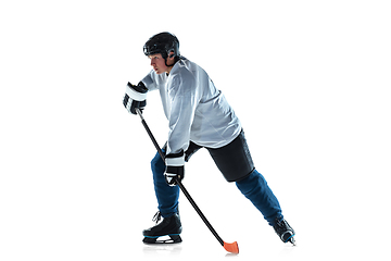 Image showing Young male hockey player with the stick on ice court and white background