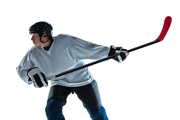 Image showing Young male hockey player with the stick on ice court and white background