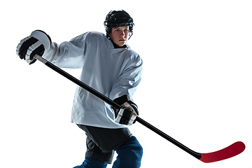 Image showing Young male hockey player with the stick on ice court and white background