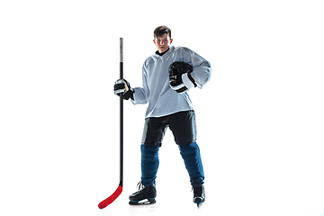 Image showing Young male hockey player with the stick on ice court and white background