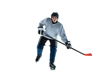 Image showing Young male hockey player with the stick on ice court and white background