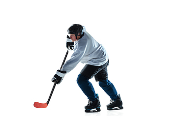 Image showing Young male hockey player with the stick on ice court and white background